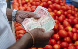 man counting money with the tomato next to him